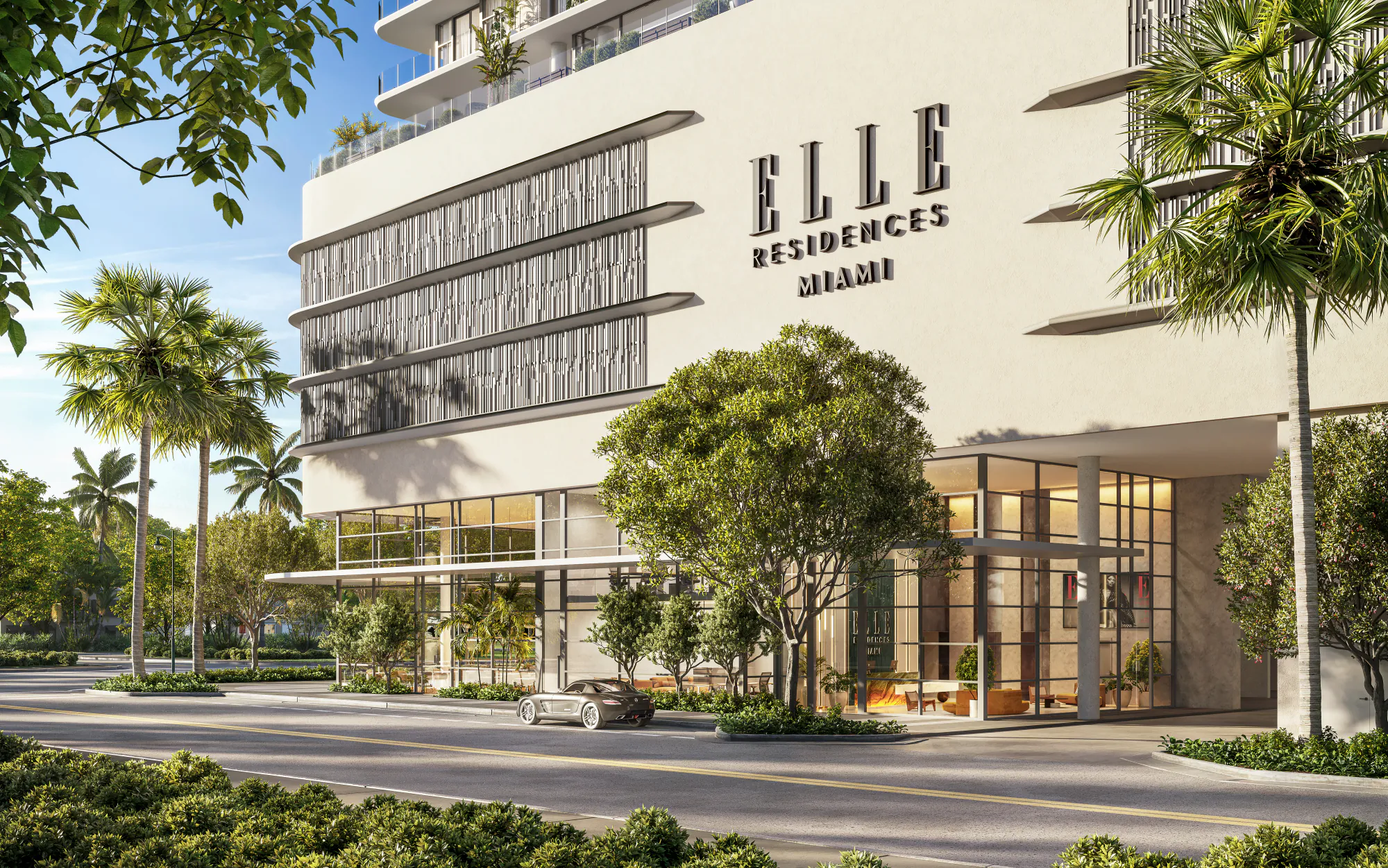 Street-level entrance to ELLE Residences Miami lined with palm trees in Edgewater